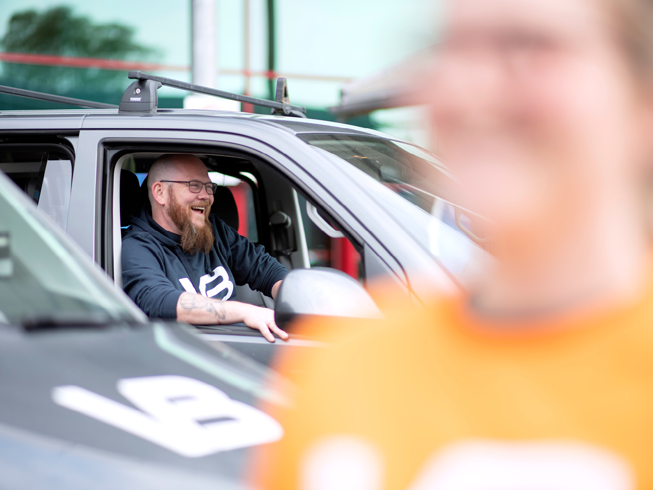 Smilende VB-rørlegger i passasjersetet på firmabilen